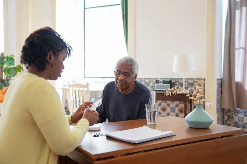 A carer sitting at a table reviewing care documentation with a service user