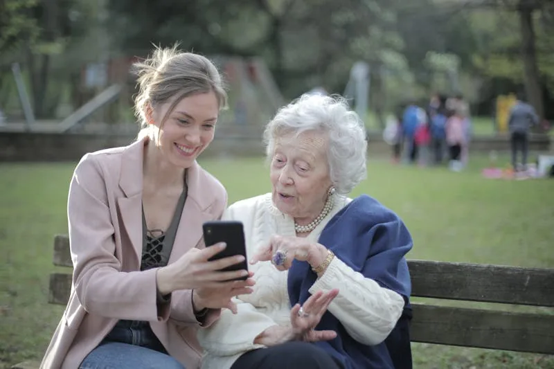 Elderly lady being helped to use a smartphone as analogue phone lines are switched off